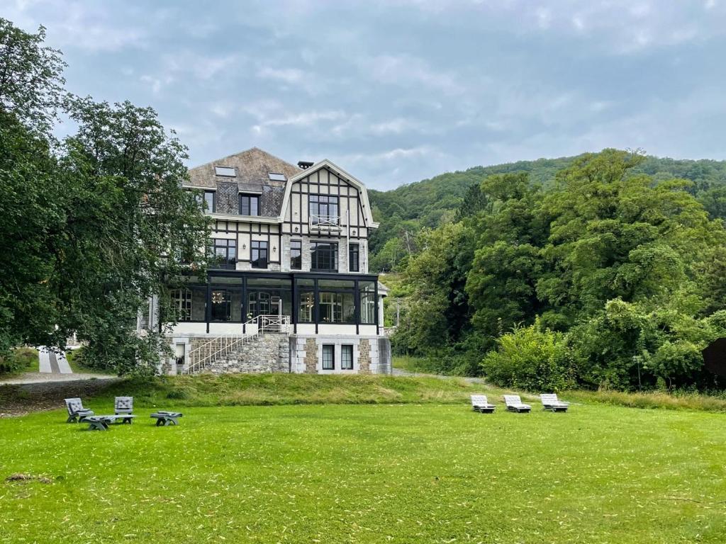 une grande maison sur un champ avec bancs devant elle dans l'établissement Villa Gracia, à Namur