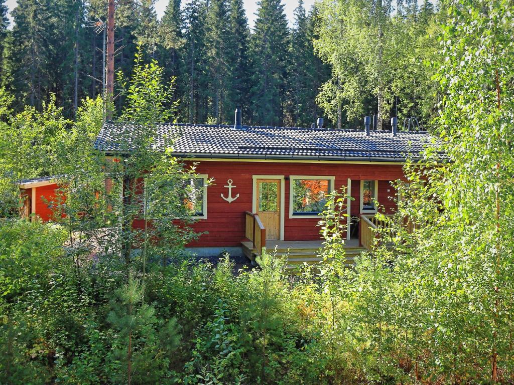 uma cabana vermelha no meio de uma floresta em Villa Anchor em Kouvola