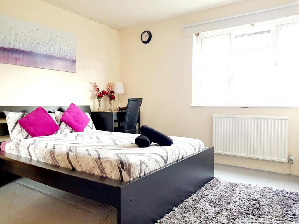 Un dormitorio con una cama con almohadas rosas y una ventana en Tower Bridge Rooms en Londres