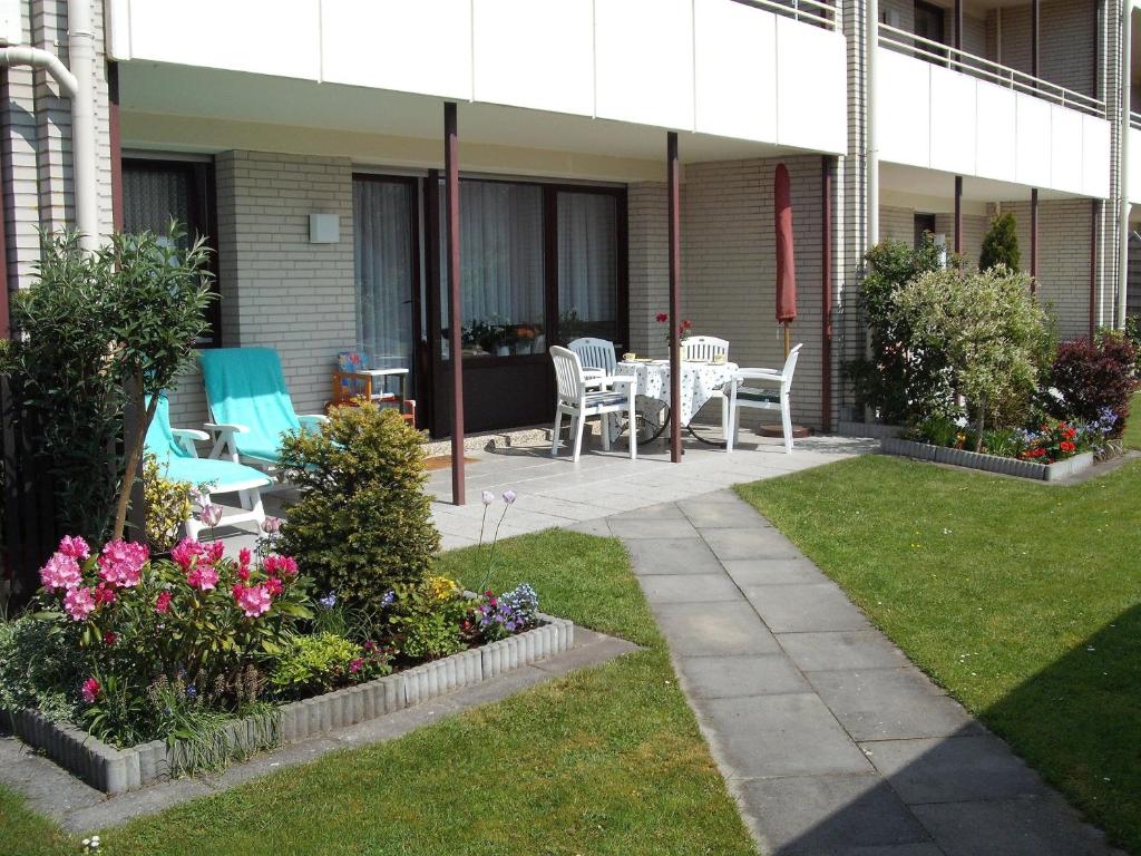 a patio with chairs and a table and flowers at Christa & Wilfried Lammermann in Hooksiel