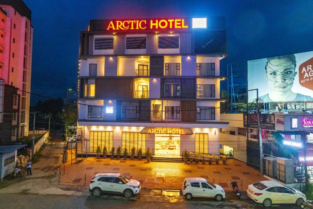 ein Hotel mit drei Autos, die davor geparkt sind in der Unterkunft Arctic Hotel in Kochi