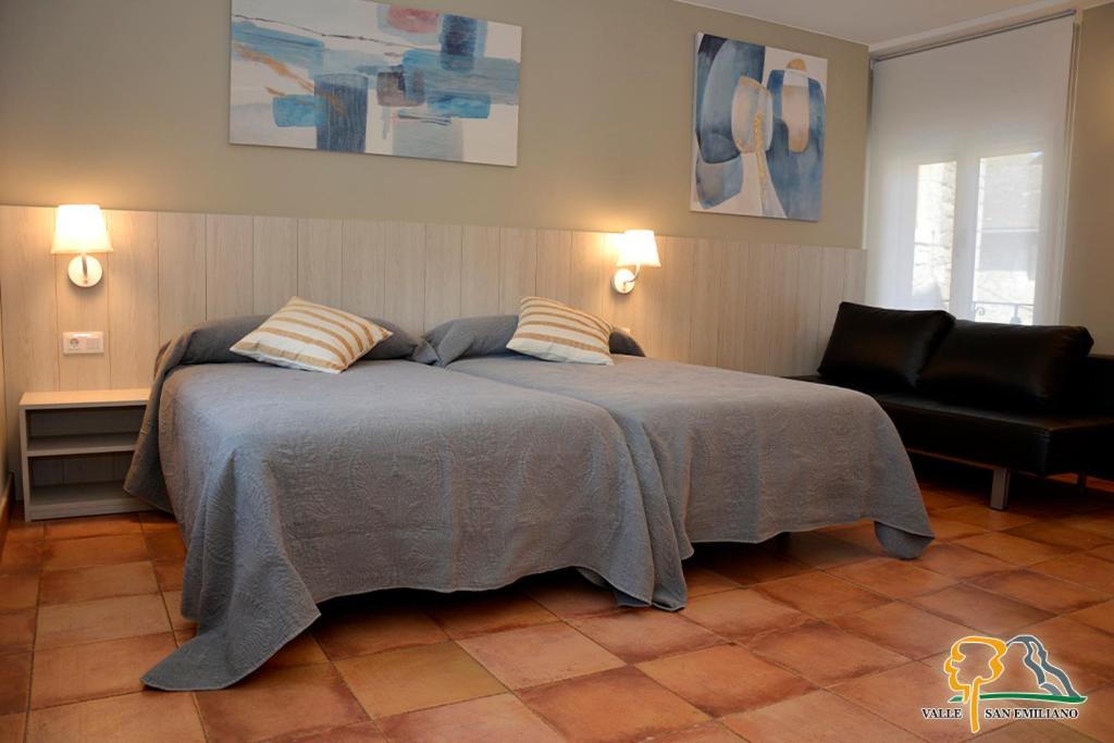 1 dormitorio con 1 cama con 2 almohadas y 1 silla en Hotel Rural Valle San Emiliano, en San Emiliano