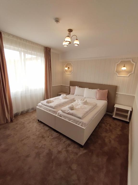 a bedroom with a large white bed with a window at Fanea Residence in Timişoara