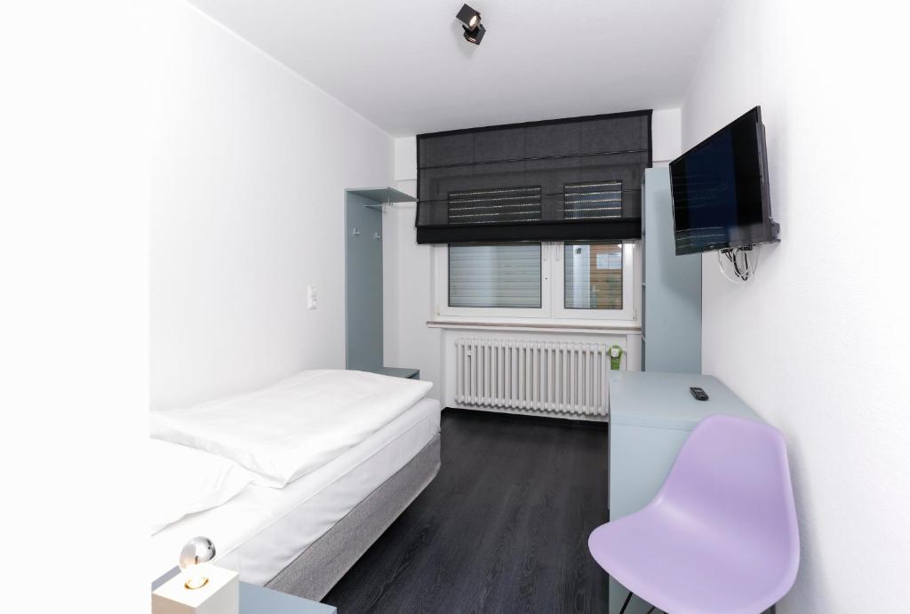 Cette petite chambre blanche dispose d'un lit et d'une télévision. dans l'établissement Die Schlafbude, à Wesseling