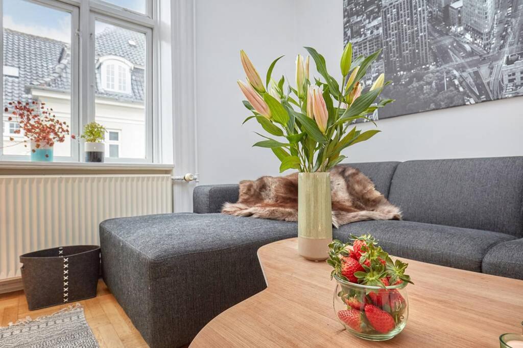a living room with a couch and a table with flowers at Central Lyngby Apartments in Kongens Lyngby