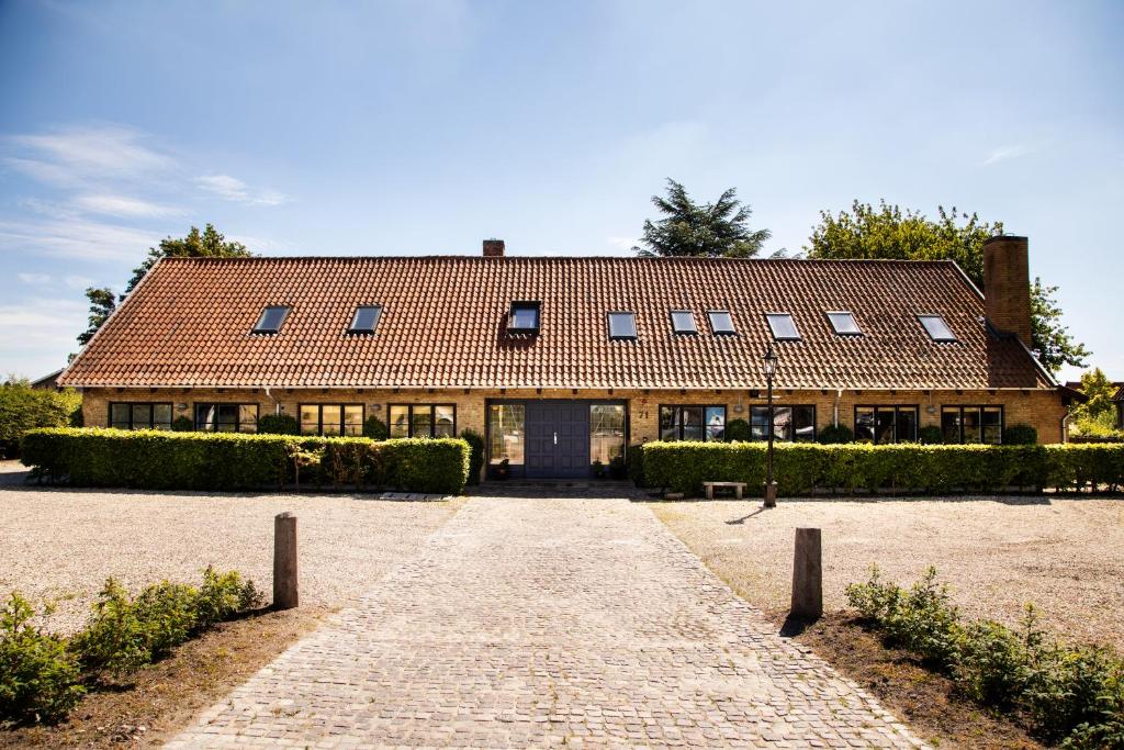 a large house with a brick driveway in front of it at Kridthuset in Rødvig