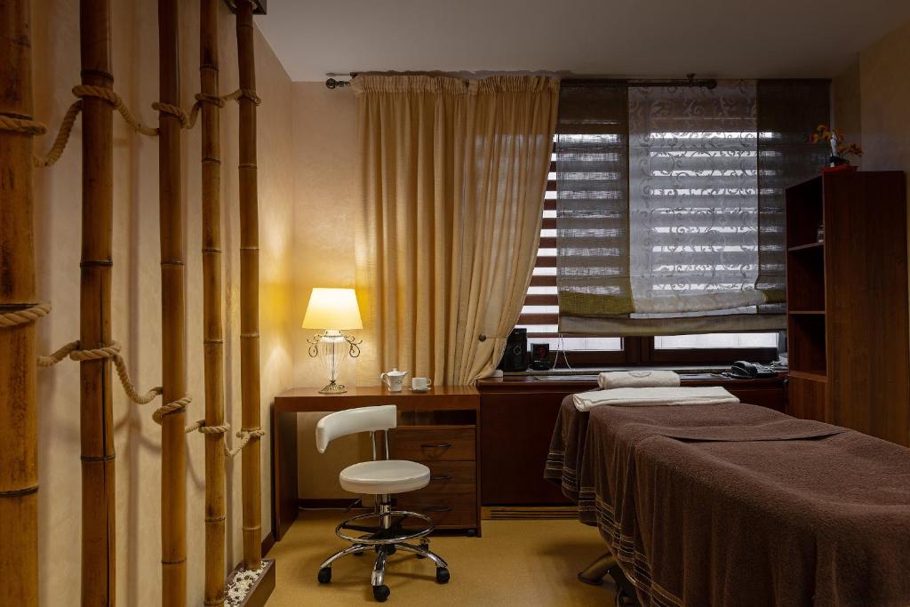 
a room with a bed, chair, desk and a window at President Hotel in Minsk
