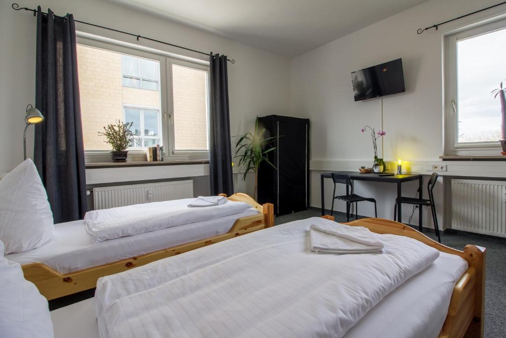 um quarto com duas camas, uma mesa e janelas em ROOM 1 / ROOM 2 em Karlsruhe