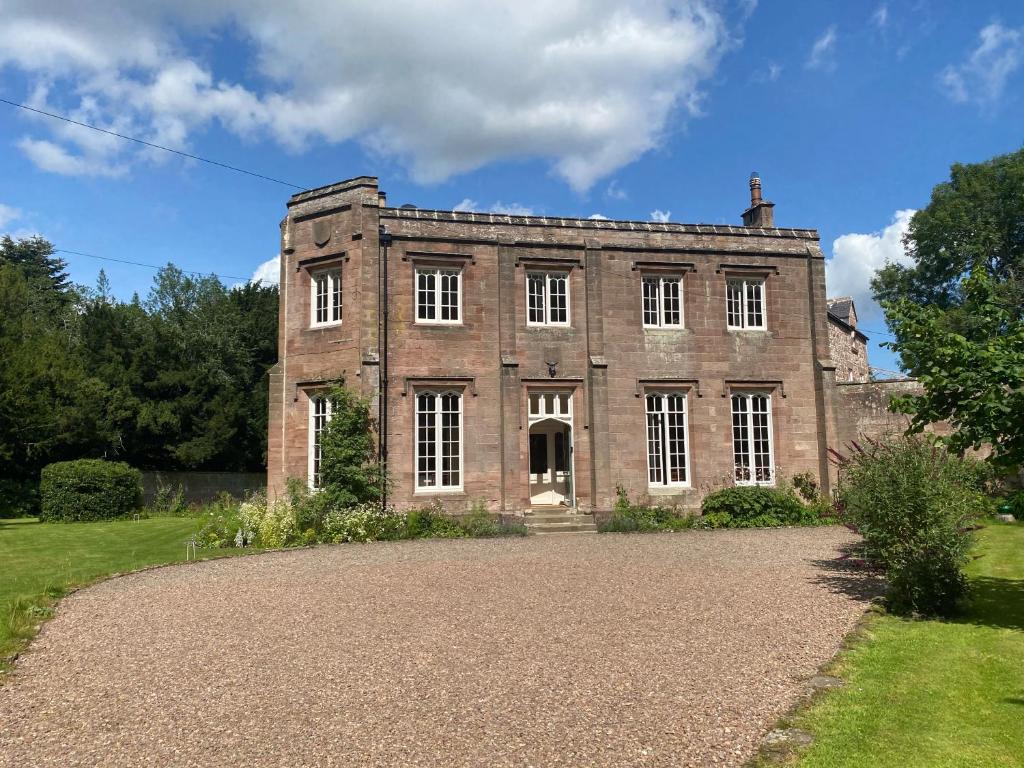 una antigua casa de ladrillo con una entrada de grava en Chillingham Manor en Chillingham