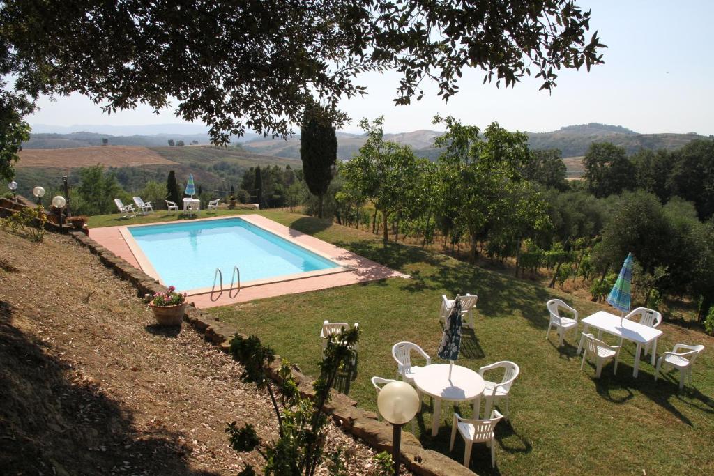 a swimming pool with tables and chairs in a garden at Agriturismo Colle Verde in Castelfalfi