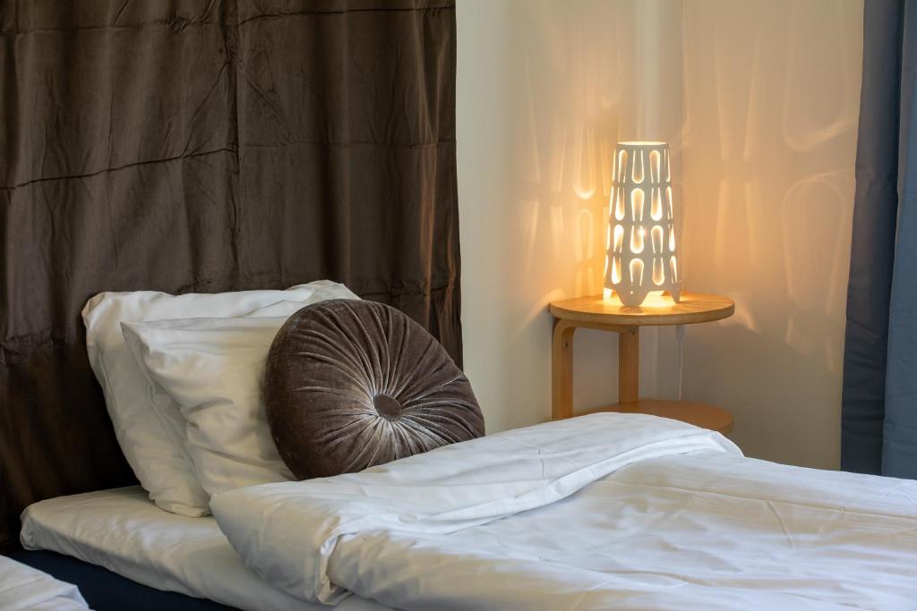 a bed with a pillow and a lamp on a table at Systemairhallen Bed&Breakfast in Skinnskatteberg