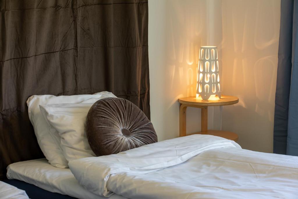 een bed met een kussen en een lamp op een tafel bij Systemairhallen Bed&Breakfast in Skinnskatteberg