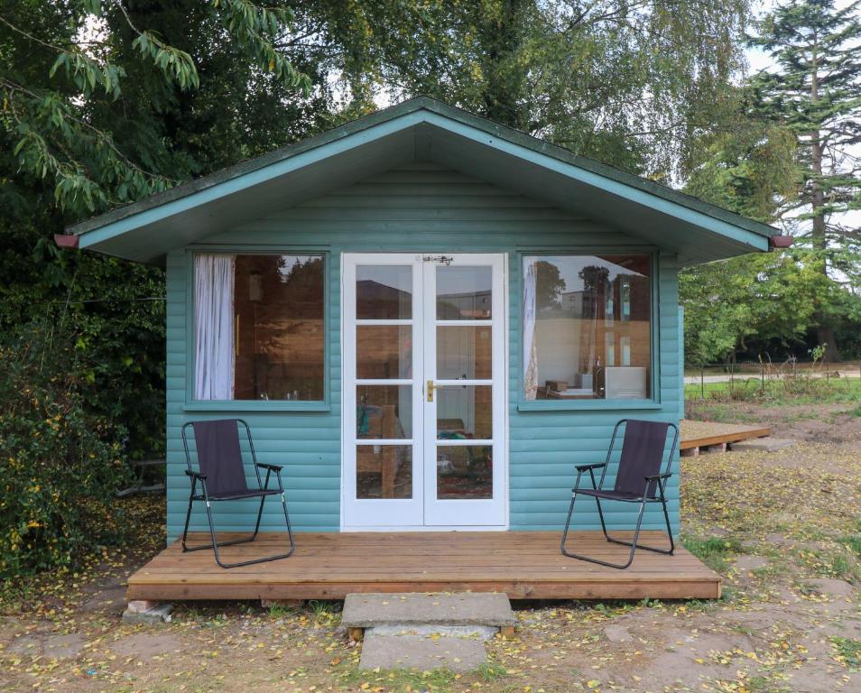 a blue tiny house with two chairs on a deck at Maid Marian's Lodge, Nottinghamshire in East Bridgford