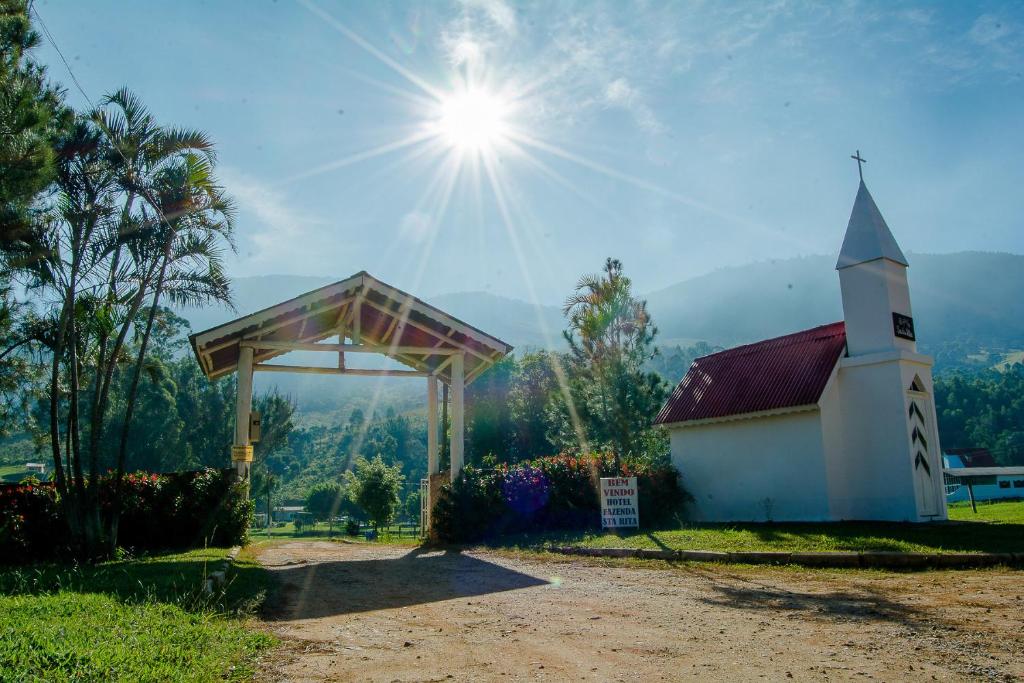 a small white church with the sun in the sky at Estancia santa Rita in Joanópolis
