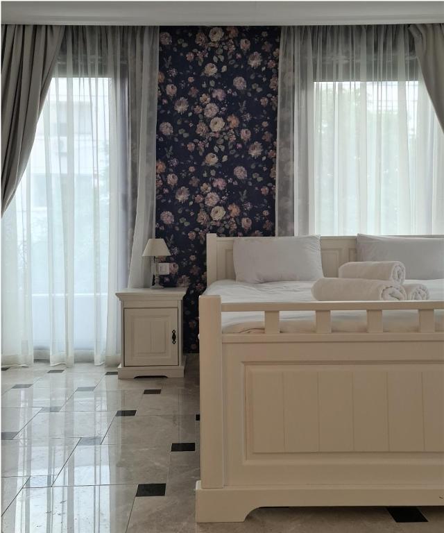 a bedroom with a large white bed and a floral wall at Kaleidoscope Boutique Hotel in Craiova