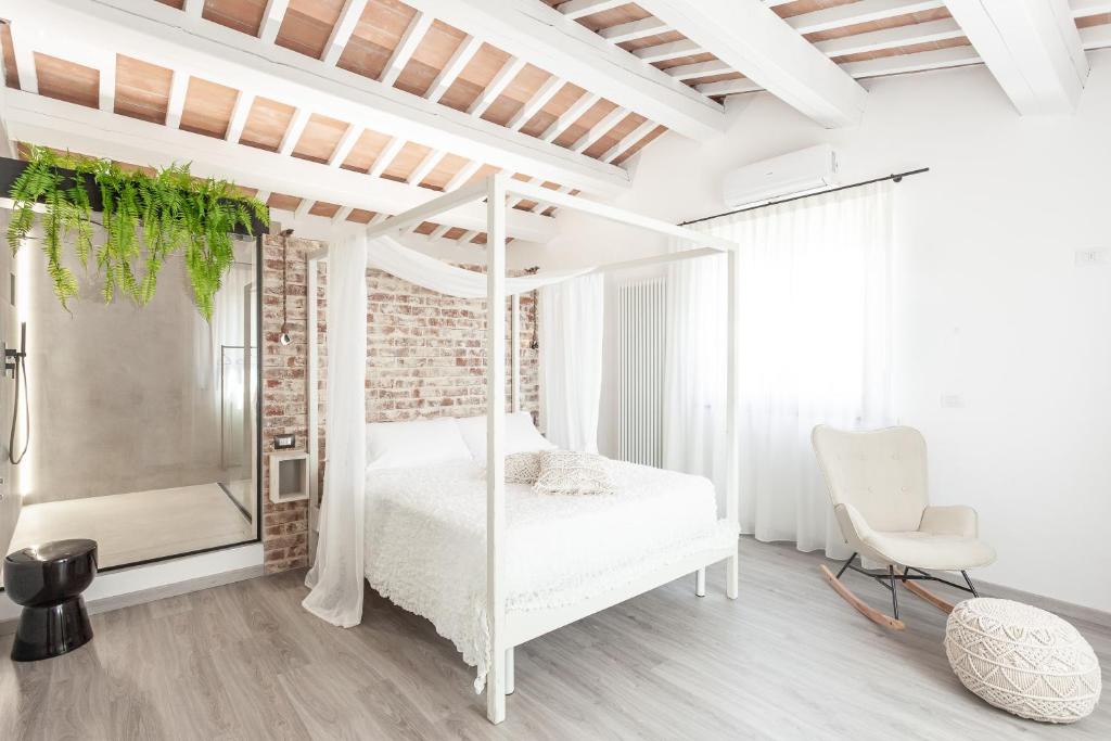 een witte slaapkamer met een bed en een stoel bij Country Rooms & Suite La Quercia in Coriano