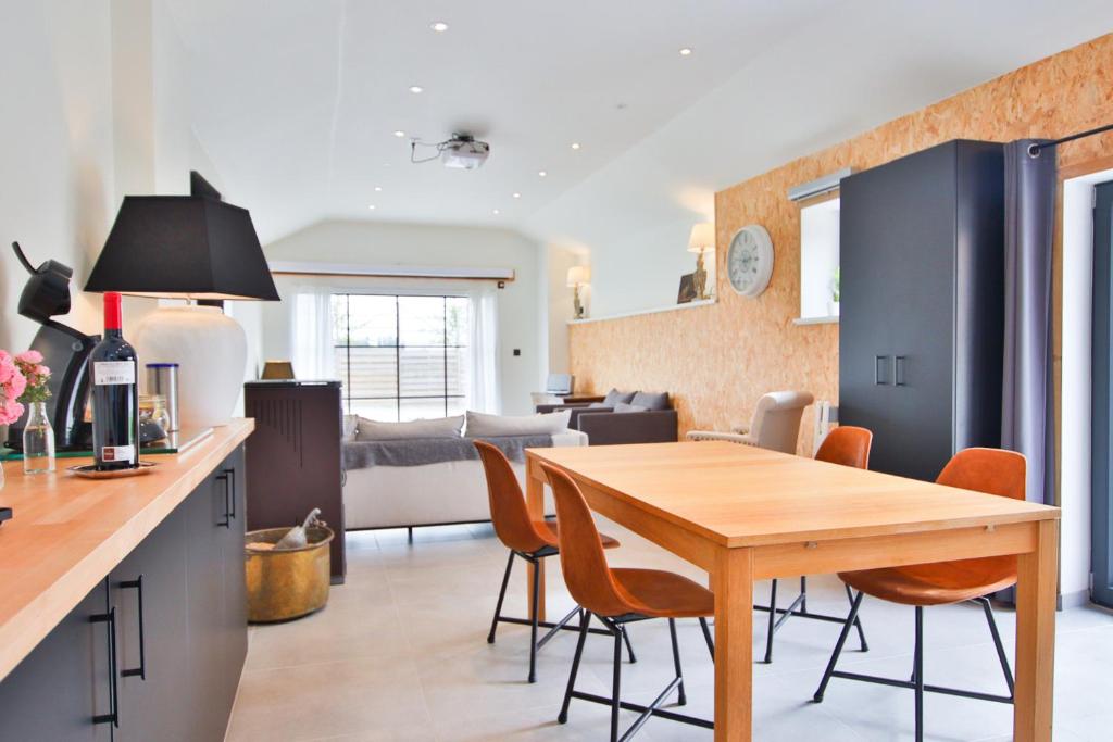 a kitchen and living room with a wooden table and chairs at La Cense de Baudecet - Les Écuries in Gembloux