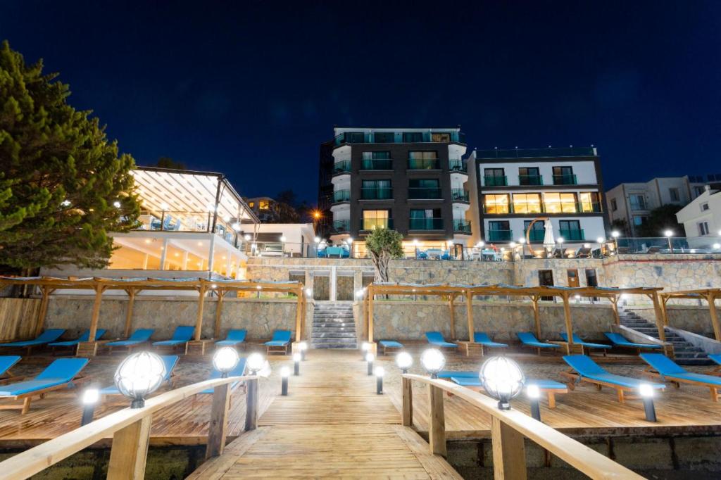 a boardwalk with chairs and lights at night at Güllük Yalı Boutique Otel in Gulluk