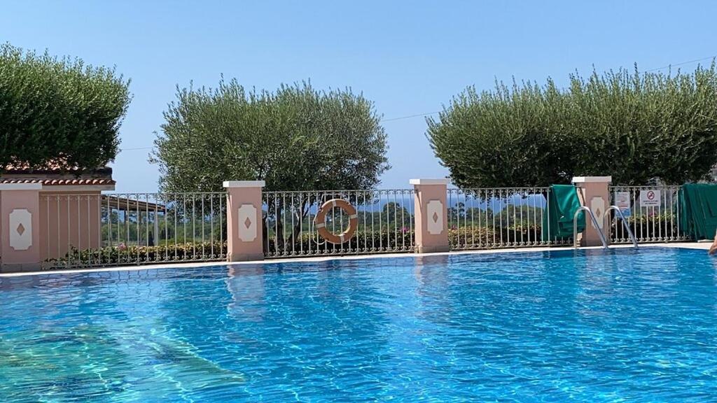 a swimming pool with a fence and blue water at Hotel Ristorante Borgo La Tana in Maratea