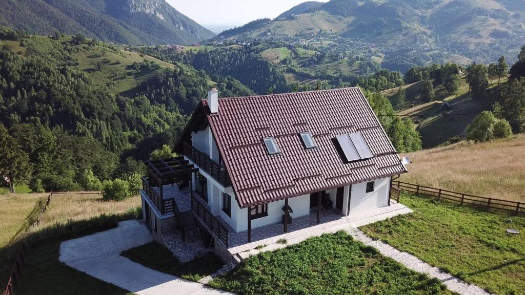 a small house on a hill with mountains in the background at Vila Pestera in Peştera