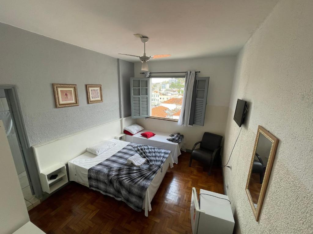 a small room with a bed and a window at Hotel Centenário in Juiz de Fora