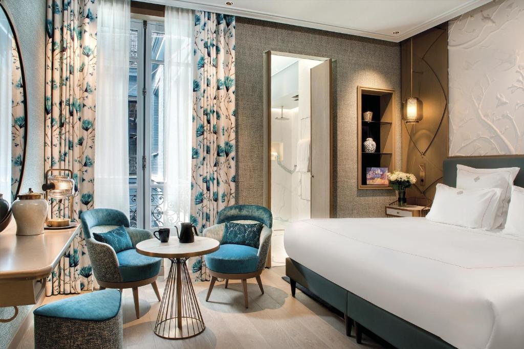 a hotel room with a bed and chairs at La Demeure Montaigne in Paris