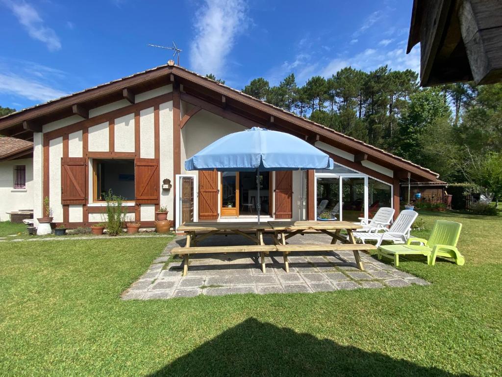 a picnic table and chairs in front of a house at Maison familiale in Soorts-Hossegor