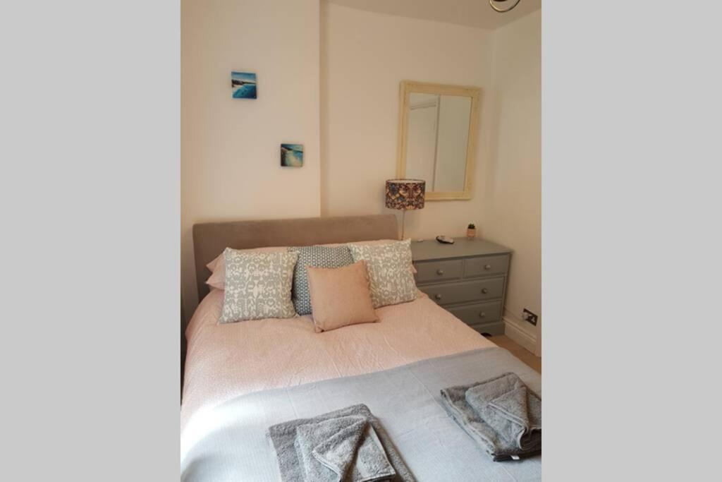 een slaapkamer met een bed, een dressoir en een spiegel bij St Ives self catering apartment private parking near beaches in St Ives