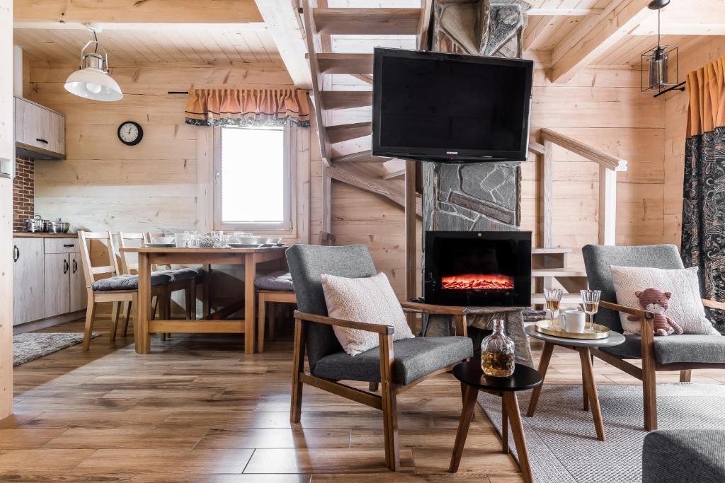 a living room with a fireplace and a dining room at Eco Domki Podhalanka in Witów