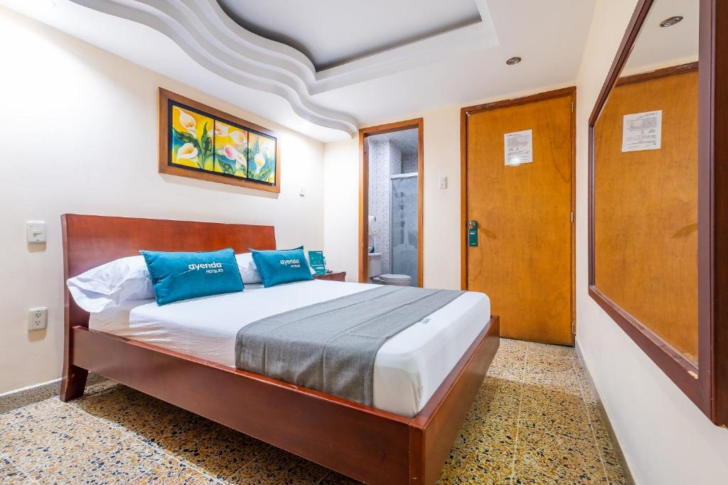 1 dormitorio con 1 cama con almohadas azules en Ayenda Almirante, en Bucaramanga