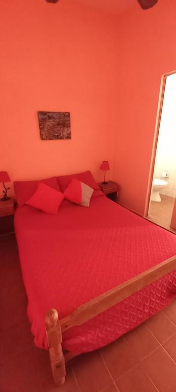 a red bed with red pillows in a bedroom at hostel Isleño in Tigre