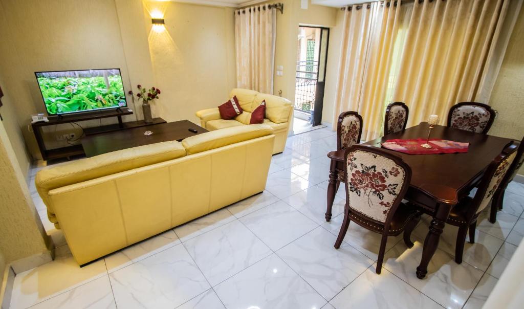 ein Wohnzimmer mit einem Sofa, einem Tisch und einem TV in der Unterkunft Residence Le Bonheur - 2 Bed Apartment by Douala Mall/Airport in Douala