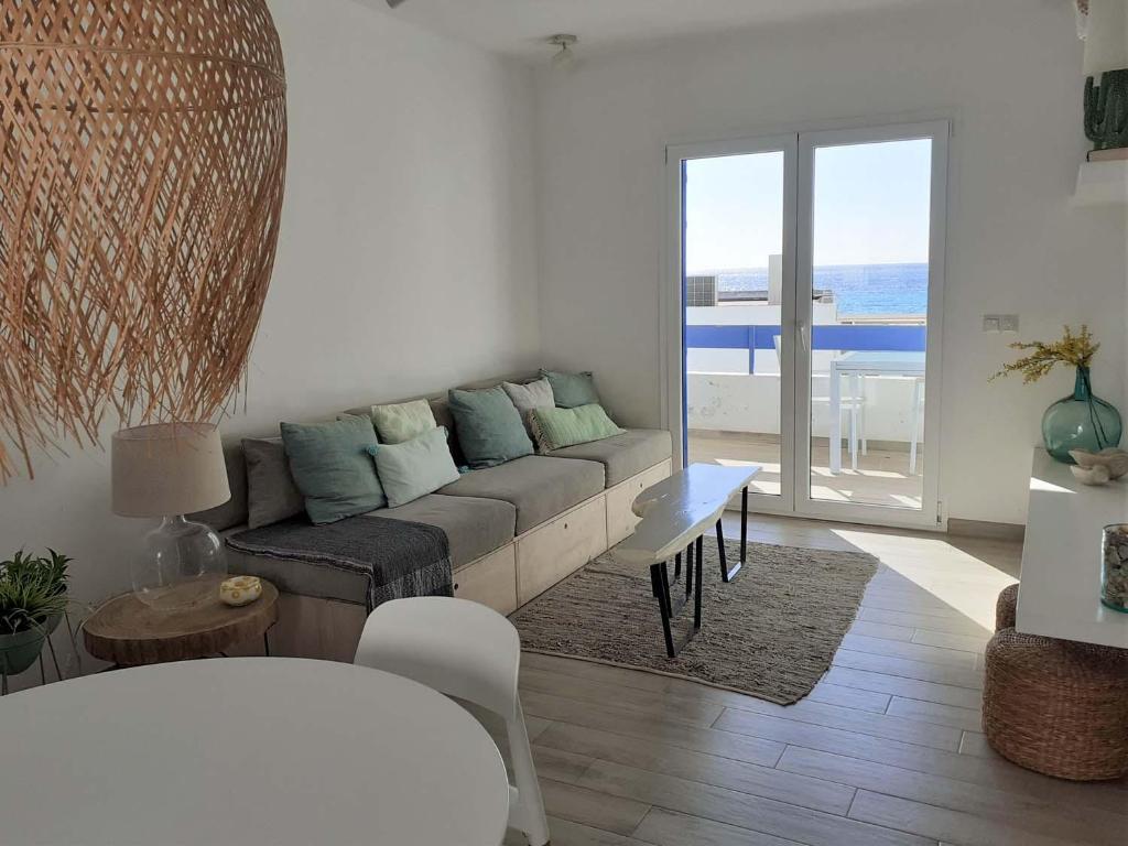 a living room with a couch and a view of the ocean at Precioso Apartamento a 20 metros del mar in Agua Amarga