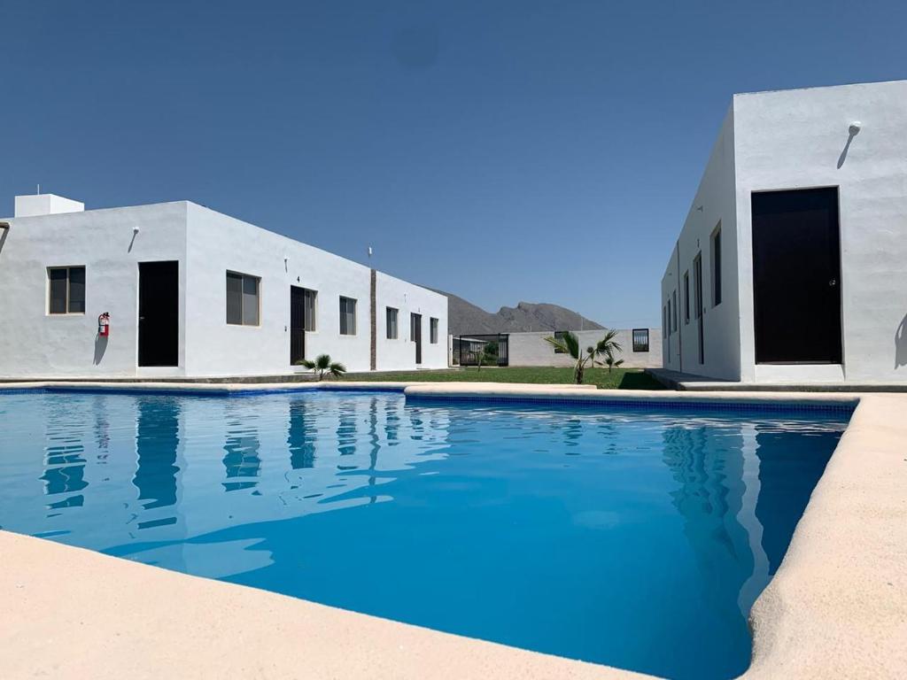 a swimming pool in front of two white buildings at Terra Viva Villa Campestre in Cuatrociénegas de Carranza
