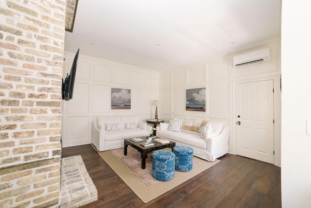a living room with white furniture and a brick wall at Guesthouse Charleston EAST 44 in Charleston