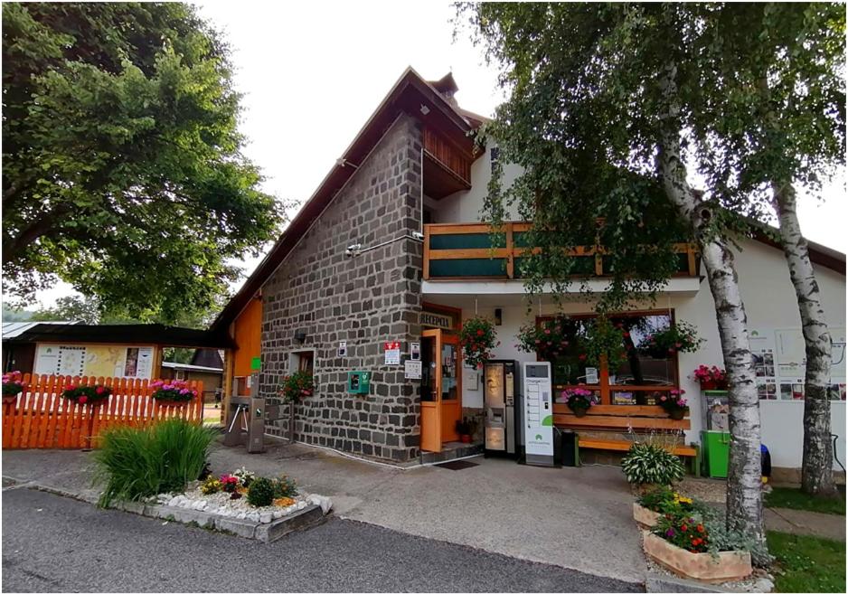 a brick building with flowers in front of it at Autocamping Podlesok in Hrabušice