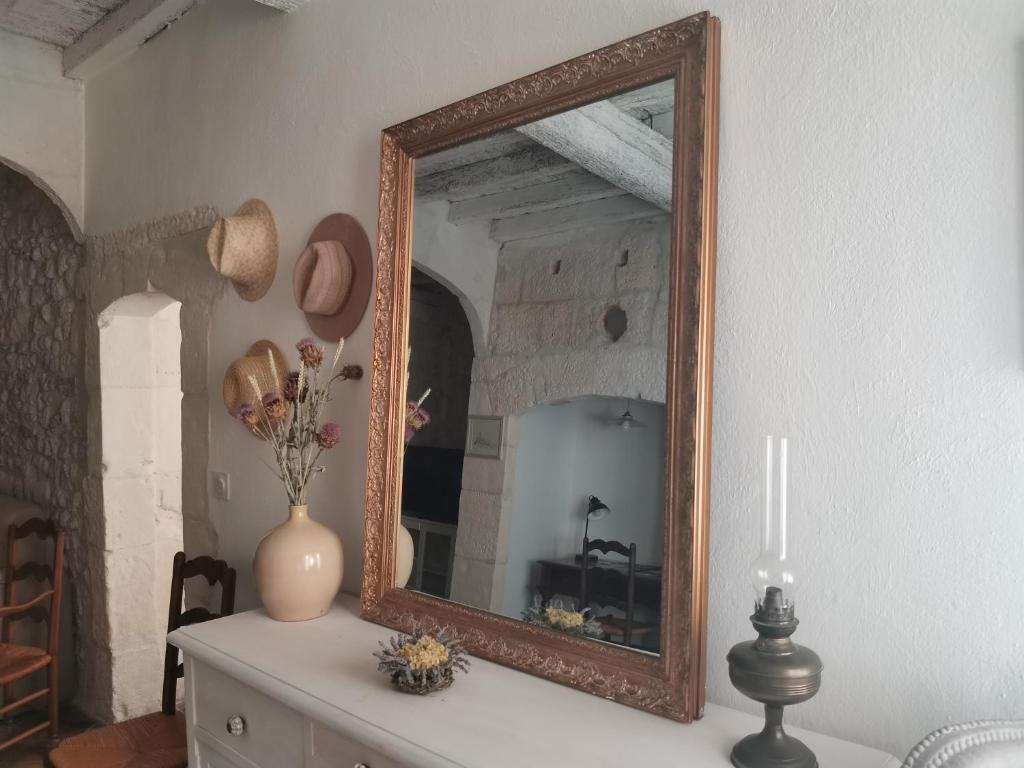 un miroir sur une table blanche avec un vase sur elle dans l'établissement L'oustaou d'Arles, à Arles