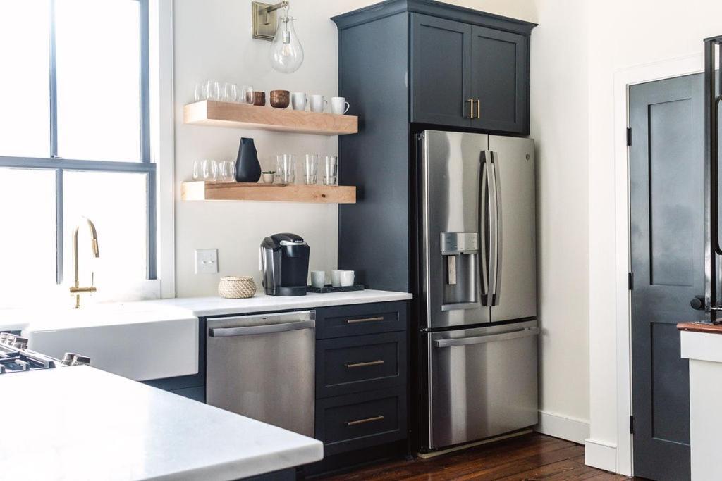 uma cozinha com armários pretos e um frigorífico de aço inoxidável em Guesthouse Charleston EAST 46 F em Charleston