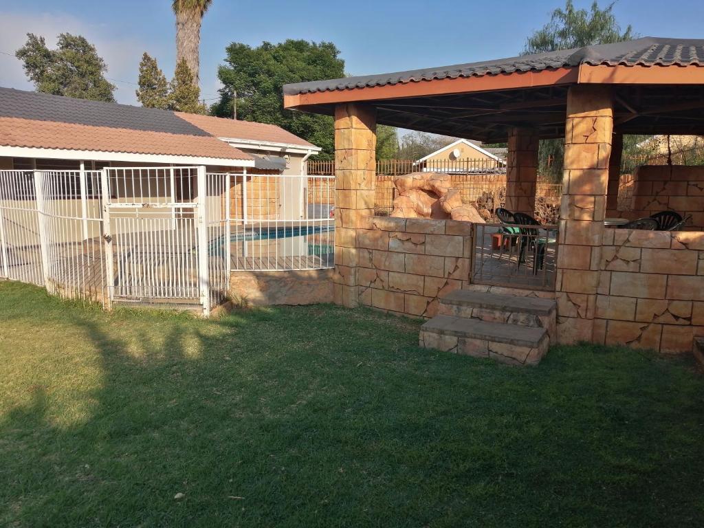 a backyard with a stone wall and a fence at Midway Overnight Rooms in Kimberley