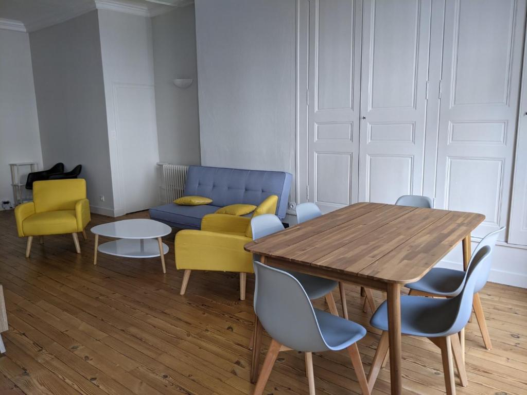 a dining room with a table and yellow chairs at Logis de la Grande Rue, appt cœur de ville, spacieux, lumineux, parquet 3 chbres, - 6 pers in La Flèche