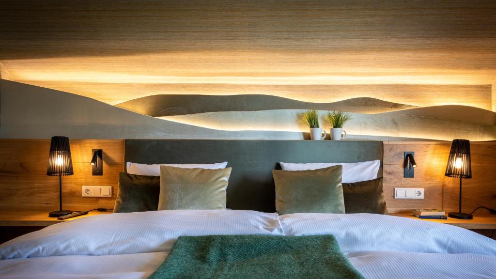 a bedroom with a large white bed with two lamps at Berggasthof & Hotel Sennhütte in Fladungen