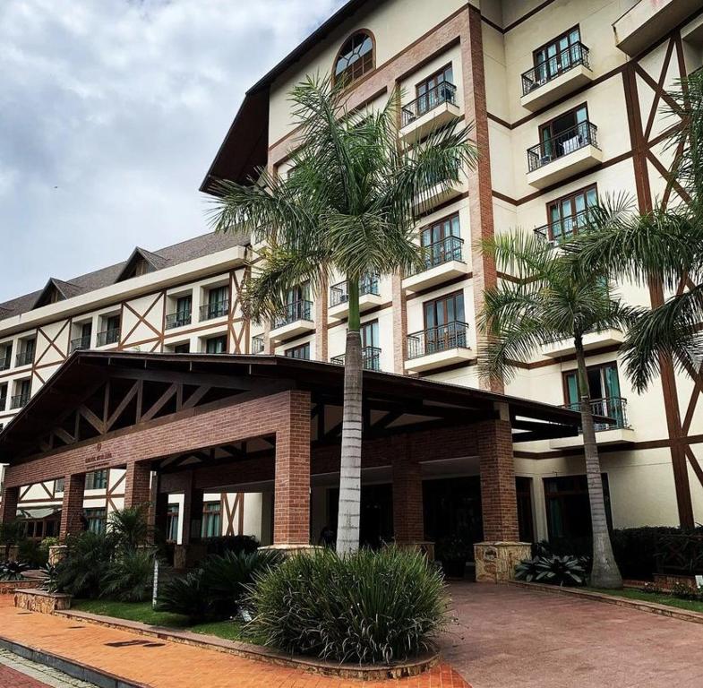 a building with palm trees in front of it at Cond Vista Azul Hotel in Pedra Azul