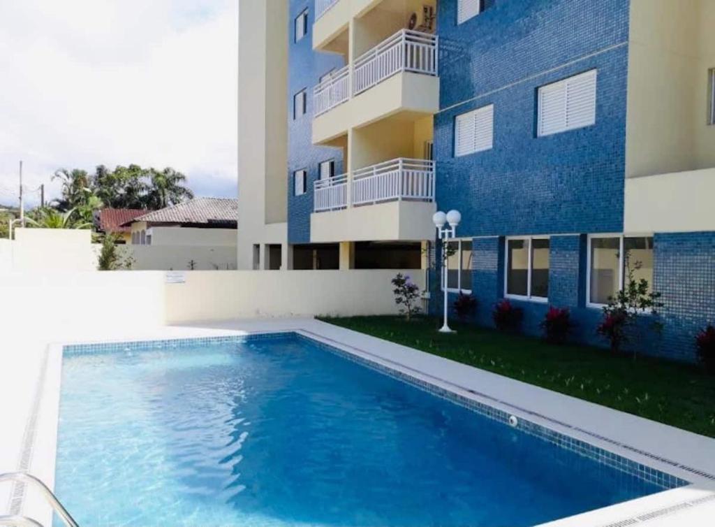 a swimming pool in front of a building at APTO FAMILIAR EM BERTIOGA JARDINS DO INDAIÁ A 500 M Praia in Bertioga