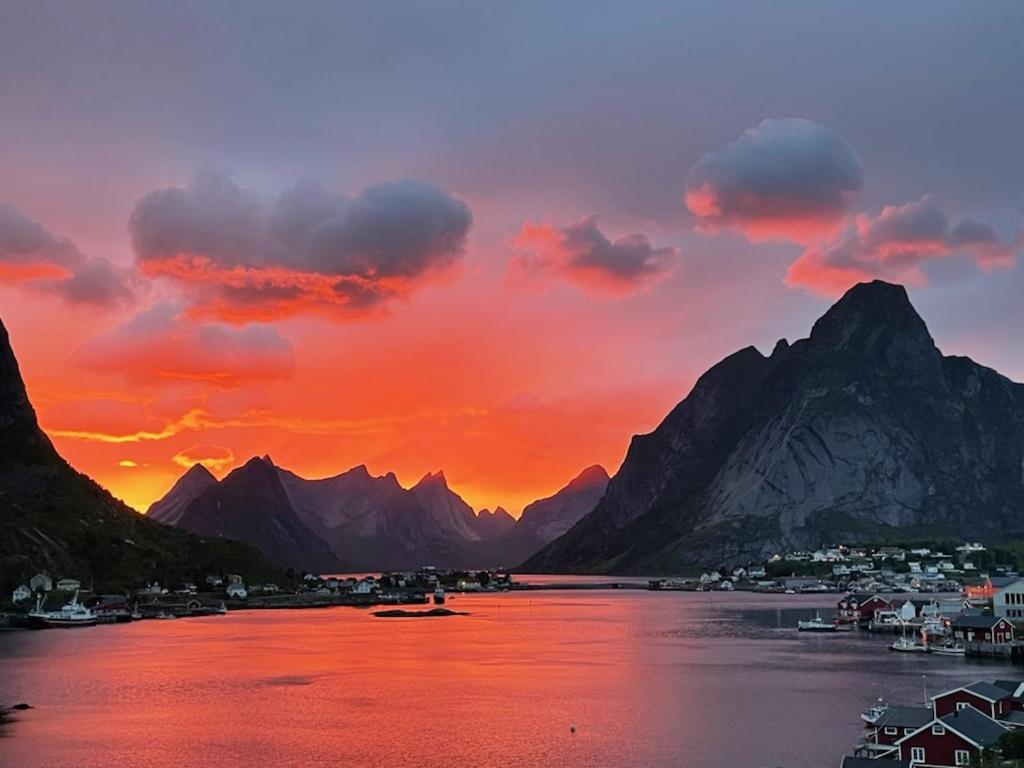 um pôr-do-sol sobre um corpo de água com montanhas em Andøy Vest Rorbuer Reine em Reine