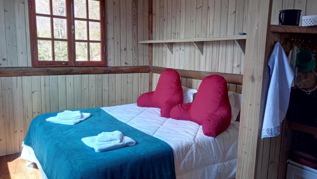 um quarto com uma cama com almofadas cor-de-rosa em Itaipava, Cabana No Alto do Vale em Itaipava