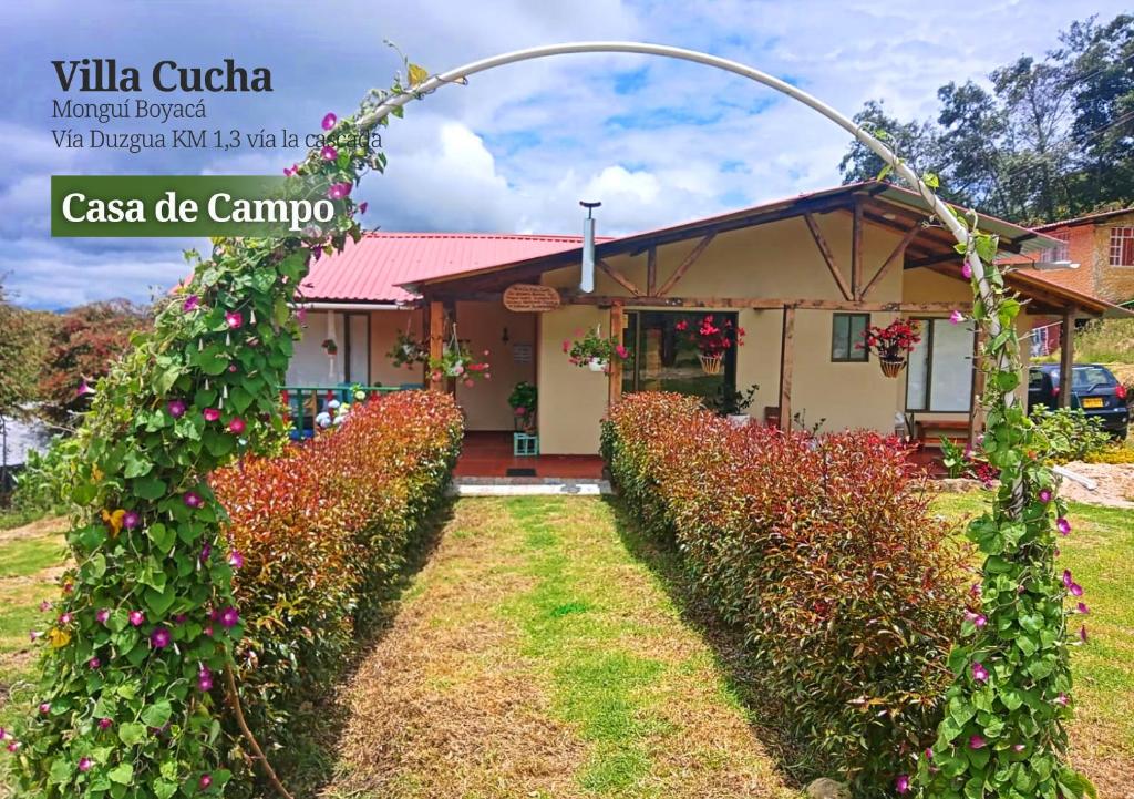 a house with a hedge of flowers in front of it at VILLA CUCHA in Monguí
