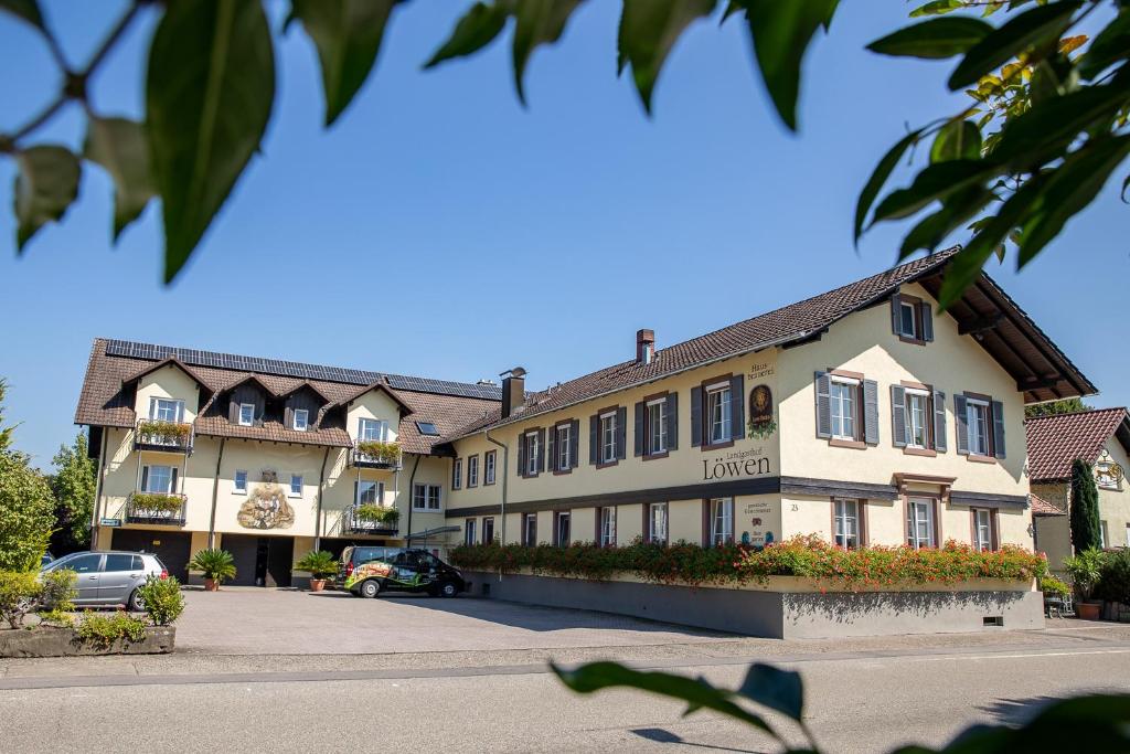 ein Gebäude mit einem Auto auf einem Parkplatz in der Unterkunft Landgasthof & Brauerei Löwen Sasbach in Sasbach in der Ortenau