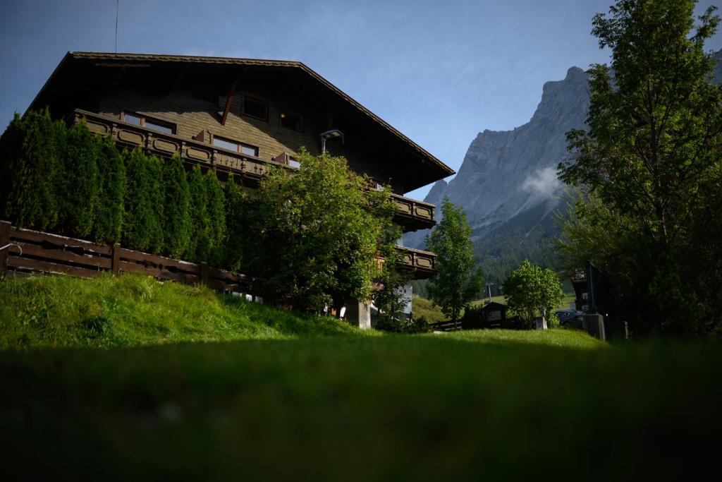 a house on a hill with a mountain in the background at Sonnenburg Hotel in Ehrwald