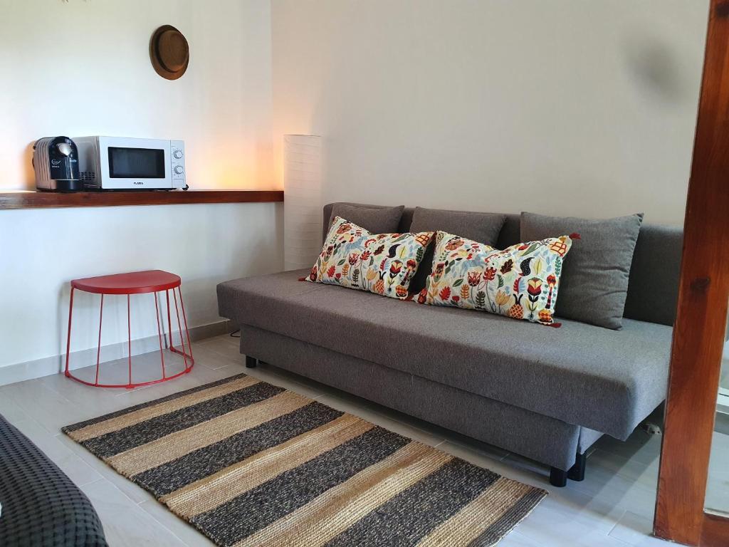 ein Sofa im Wohnzimmer mit einem roten Stuhl in der Unterkunft Aldeia Studio Albufeira in Albufeira