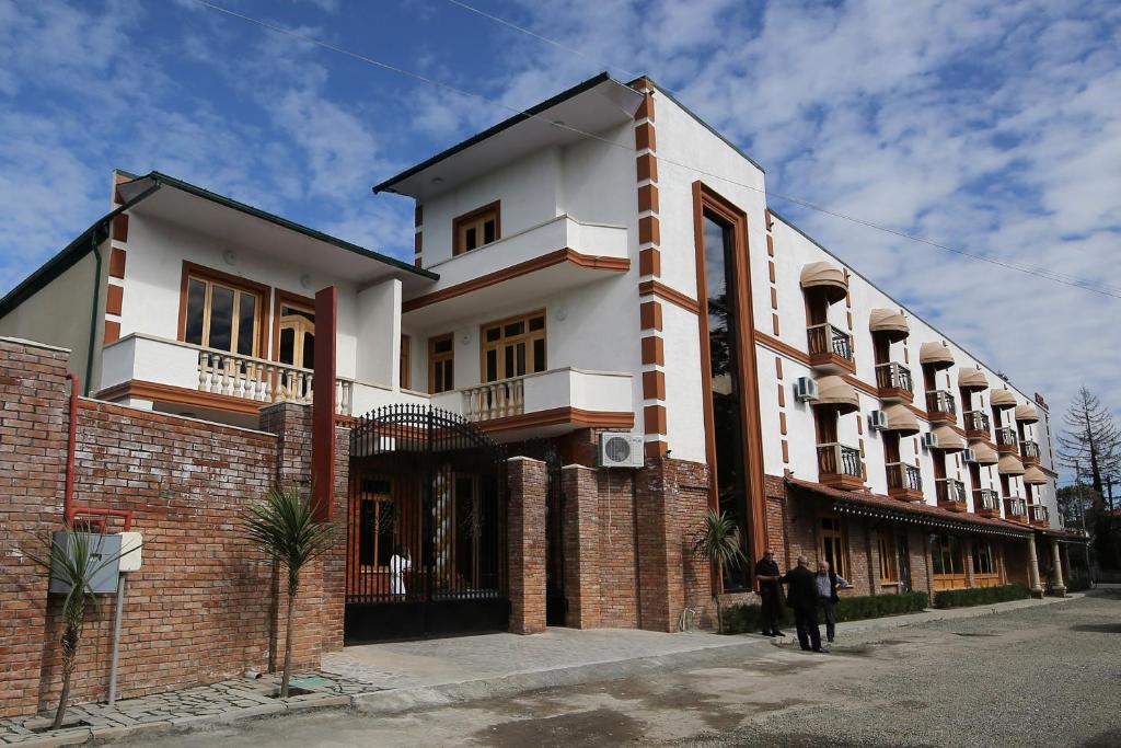 dos personas parados frente a un edificio en Hotel Shogi en Zugdidi